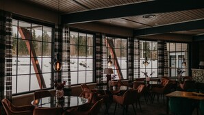 Un restaurant amb grans finestres, sostre de fusta i mobiliari modern.