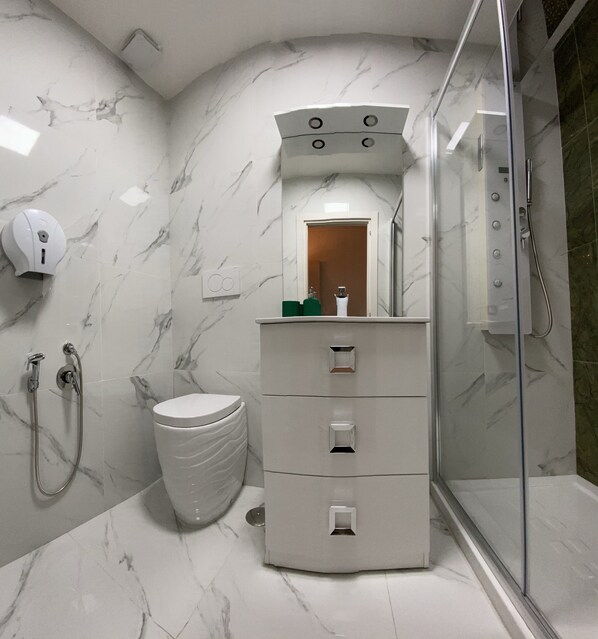 A bathroom with a marble floor, a toilet, a sink with a mirror, and a shower area. - The Place in Rome (Rome)