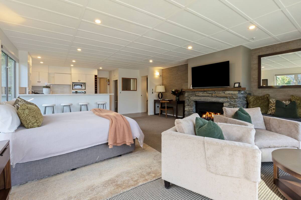 Ett modernt hotellrum med en stor säng, en soffa, en öppen spis och en tv.