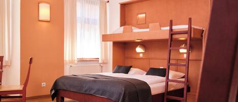 Ein Zimmer mit einem Etagenbett, einem Holzstuhl, einem Heizkörper und einem Fenster mit Vorhängen.
