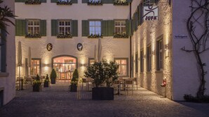 Un patio de hotel con asientos exteriores, un letrero que dice 'JUFA' y un camino adoquinado.