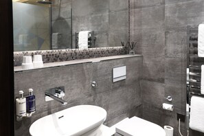Un baño moderno con lavamanos blanco, inodoro y zona de ducha.