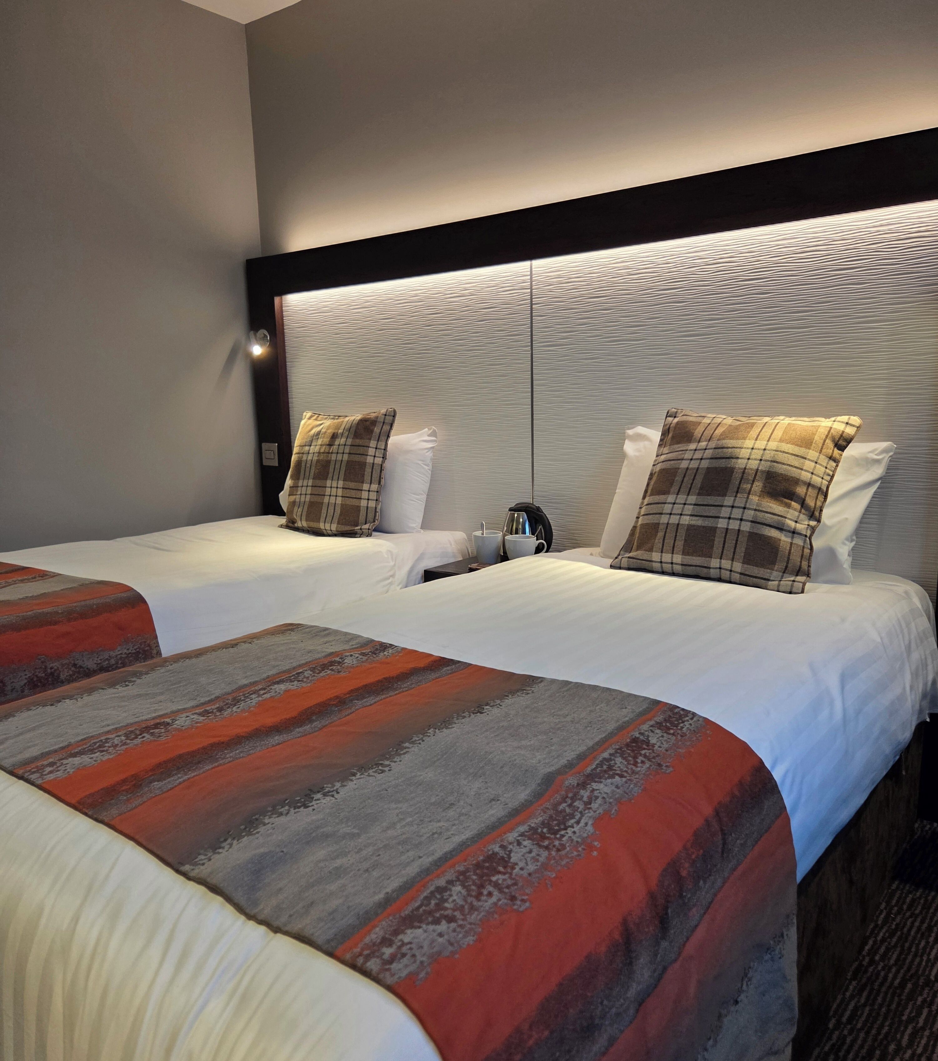 Een hotelkamer met twee bedden, een modern hoofdbord en een groot raam.