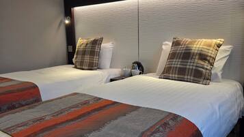 Een hotelkamer met twee bedden, een modern hoofdbord en een groot raam.