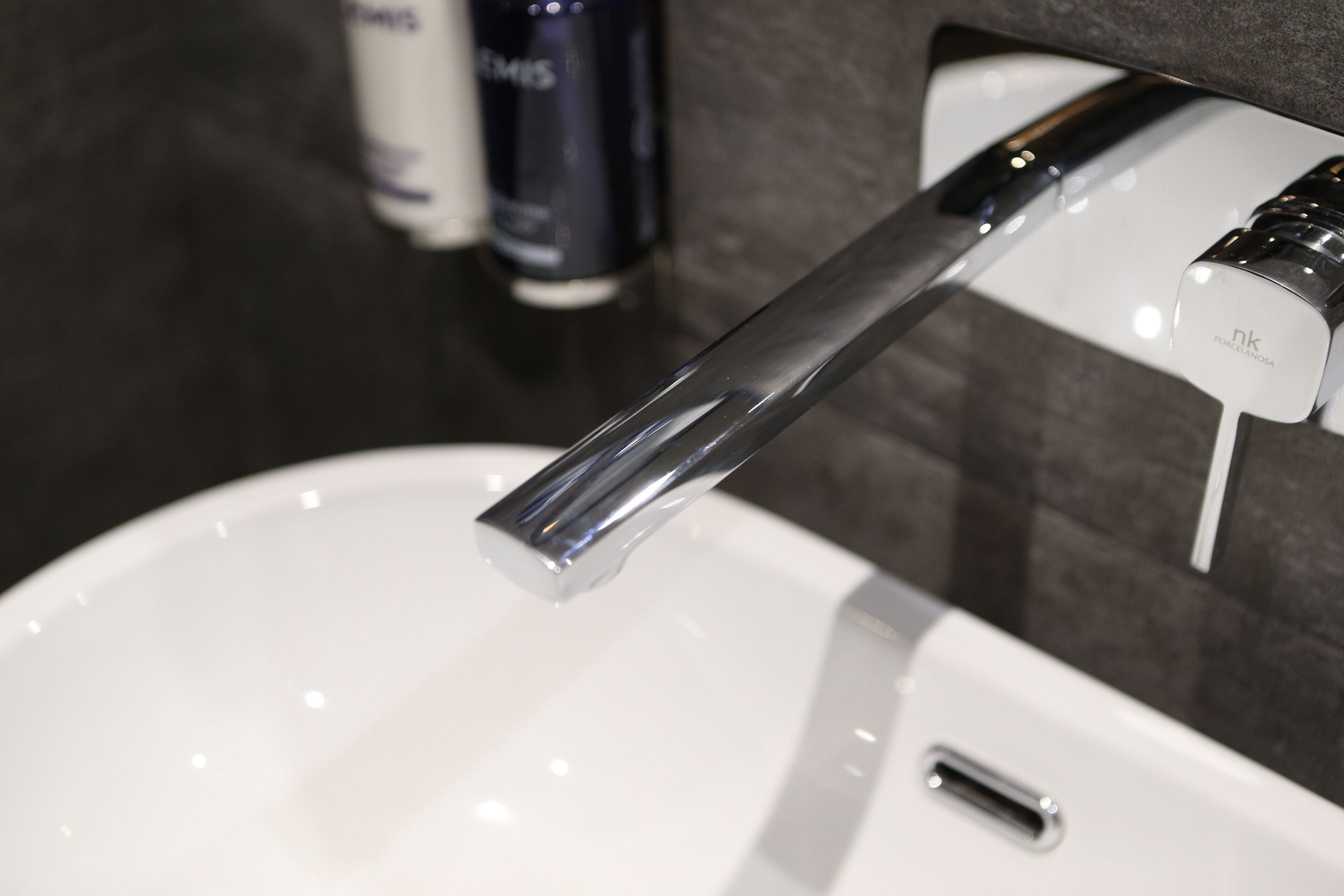 Een moderne wastafel met een chromen kraan en een zeepdispenser.