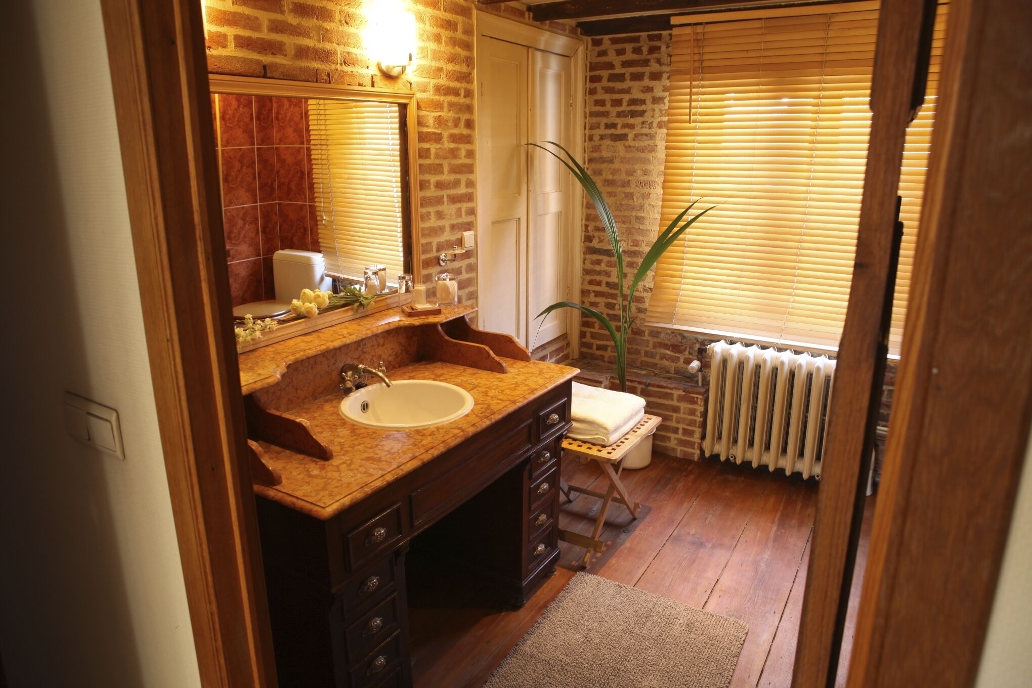 A bathroom with a wooden vanity, a sink, a mirror, and a radiator.