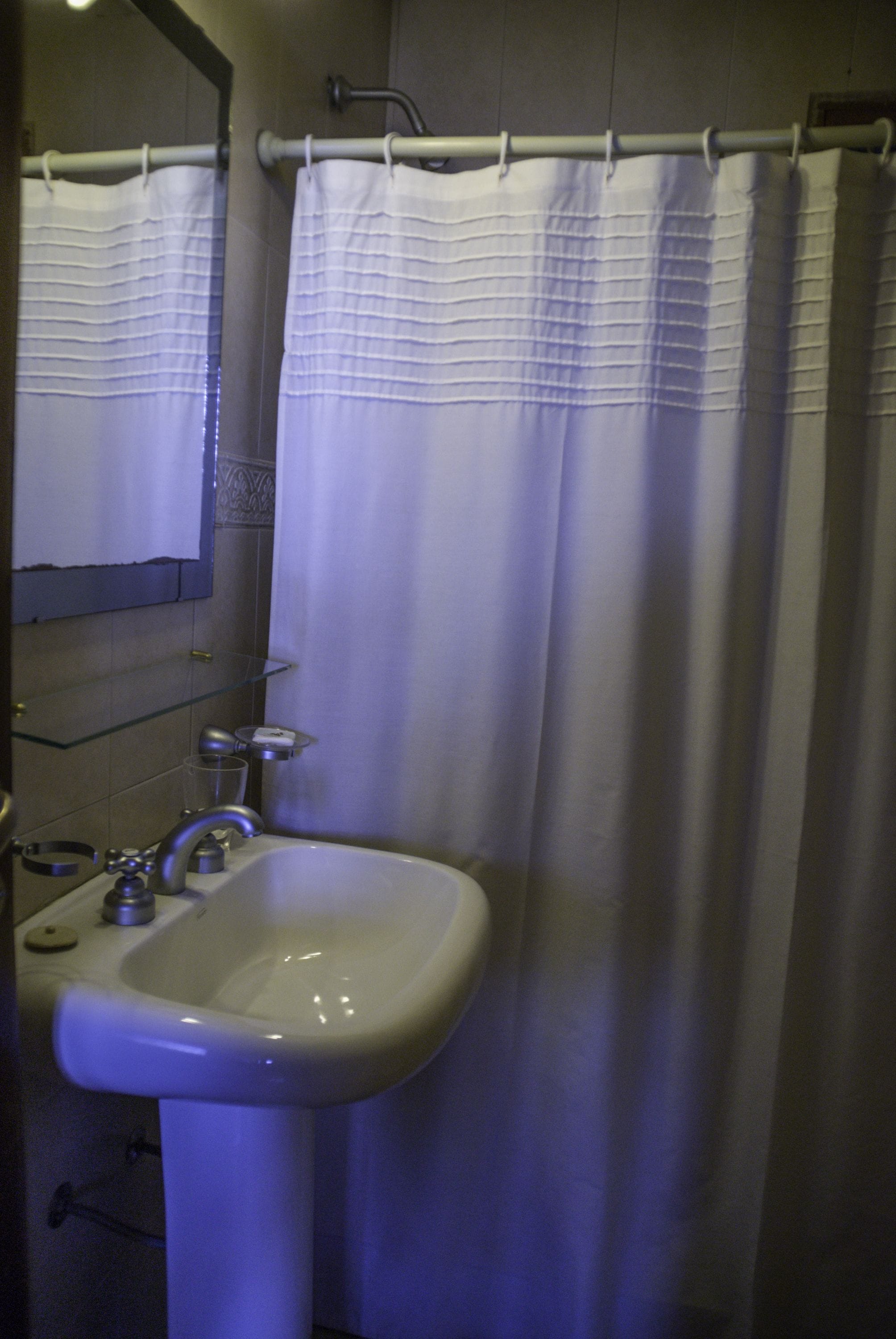 A bathroom with a white sink, a mirror, and a shower curtain.