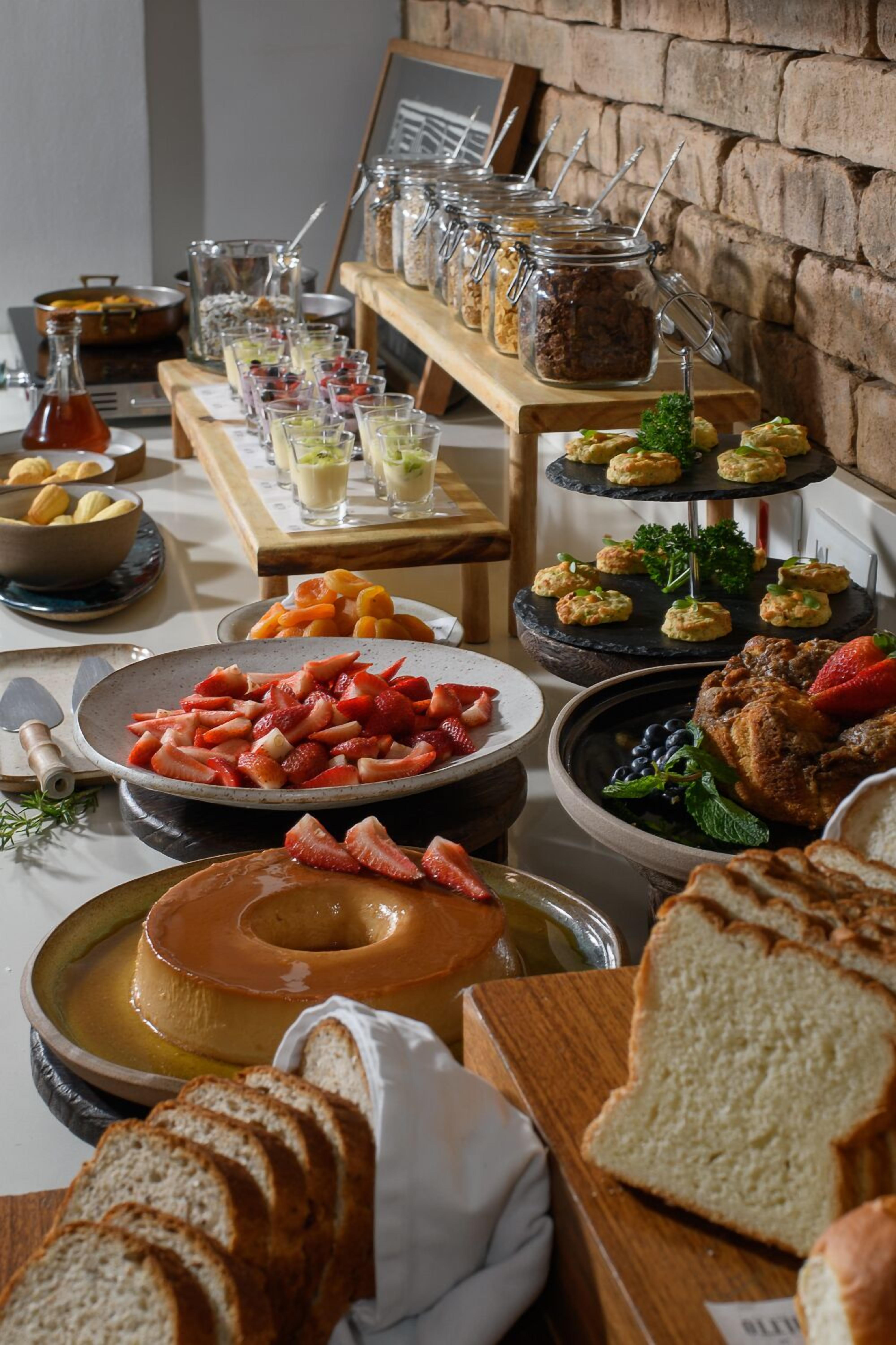 Ein Buffet mit verschiedenen Speisen, darunter eine große Schale Erdbeeren, eine Suppe und mehrere kleine Schälchen auf einer Etageren.
