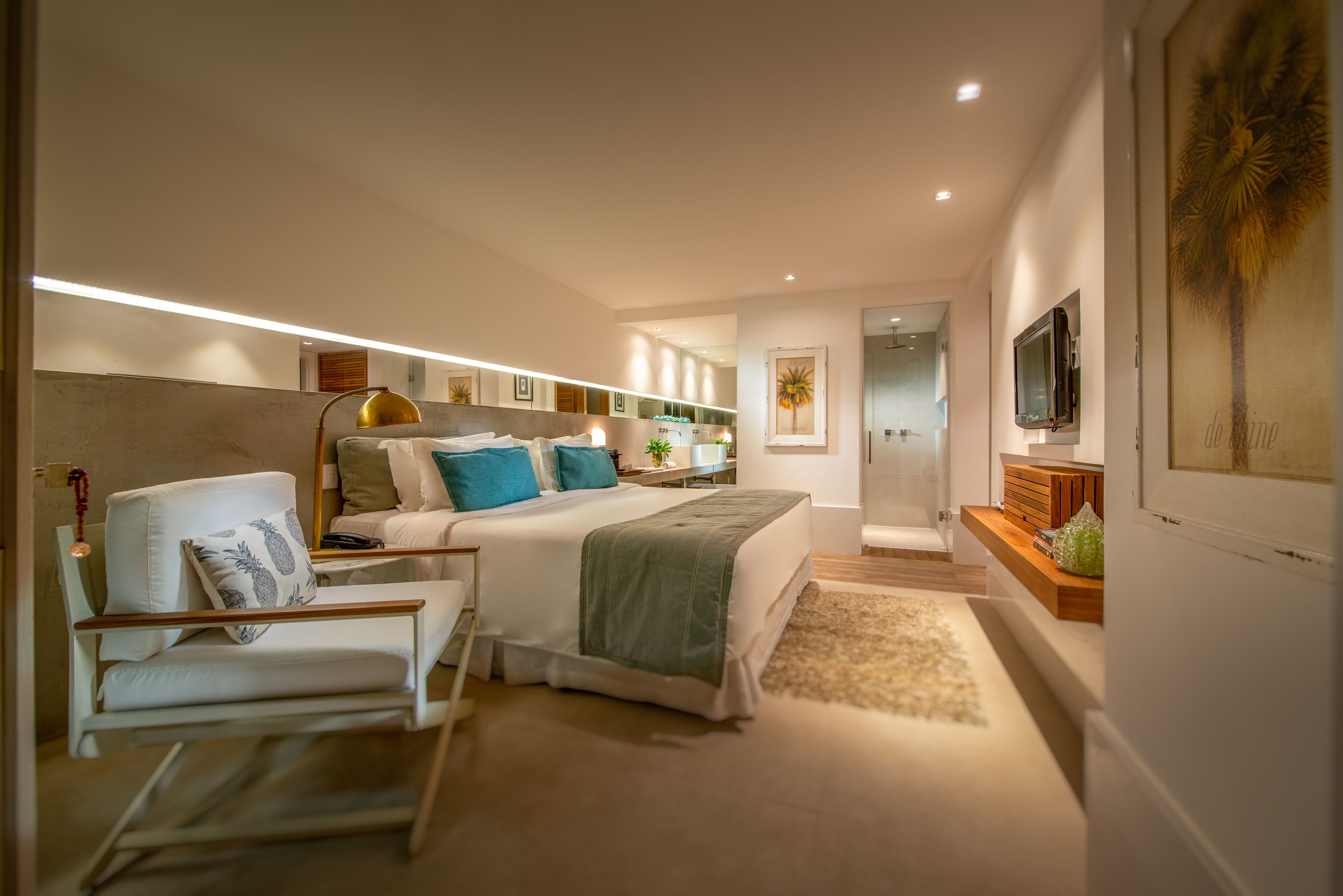 A modern bedroom with a bed, bedside table, chair, and a TV on the wall.