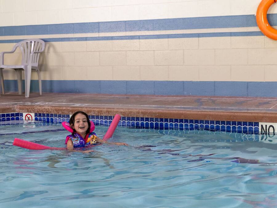 Una piscina con un niño usando una tabla de natación.