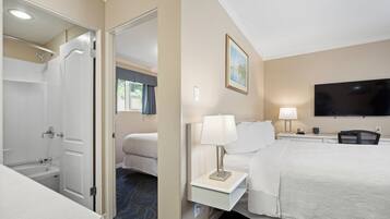 A hotel room with a bed, bedside tables, a TV, and a bathroom with a shower and toilet.