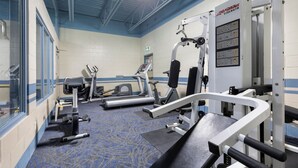 A gym with exercise equipment, a blue carpet, and a white wall with blue trim. - Glenwood Inn & Suites (Trail)