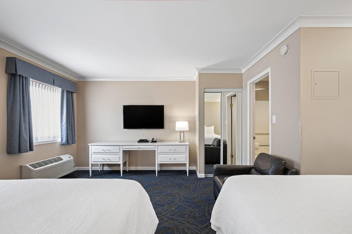 Ett hotellrum med två sängar, ett skrivbord, en TV och en stol.