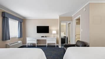 A hotel room with two beds, a desk, a TV, and a chair.