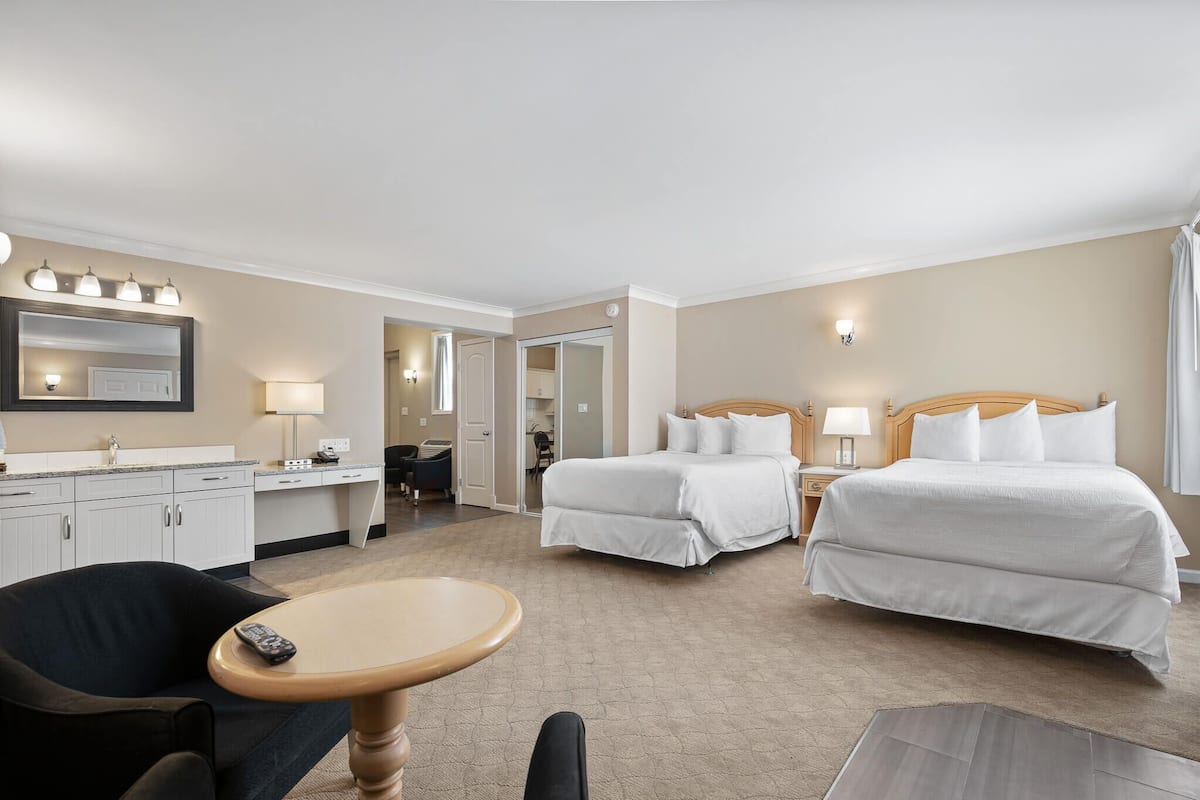 Ett hotellrum med två sängar, ett skrivbord, en stol, ett bord och en spegel.