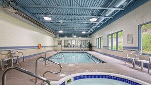A swimming pool with a tiled edge, a hot tub, and a ceiling with visible beams and lighting fixtures. - Glenwood Inn & Suites (Trail)
