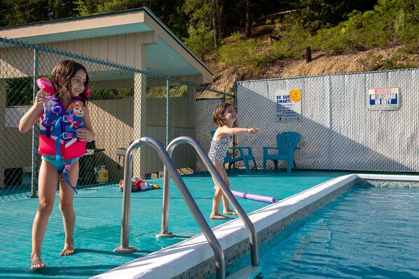 A swimming pool with a fence, a lifeguard chair, and a sign indicating no lifeguard on duty.