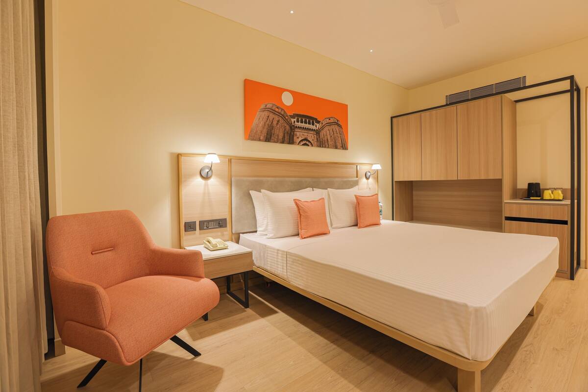 Una habitación de hotel con una cama, una silla, una mesita de noche y un armario.