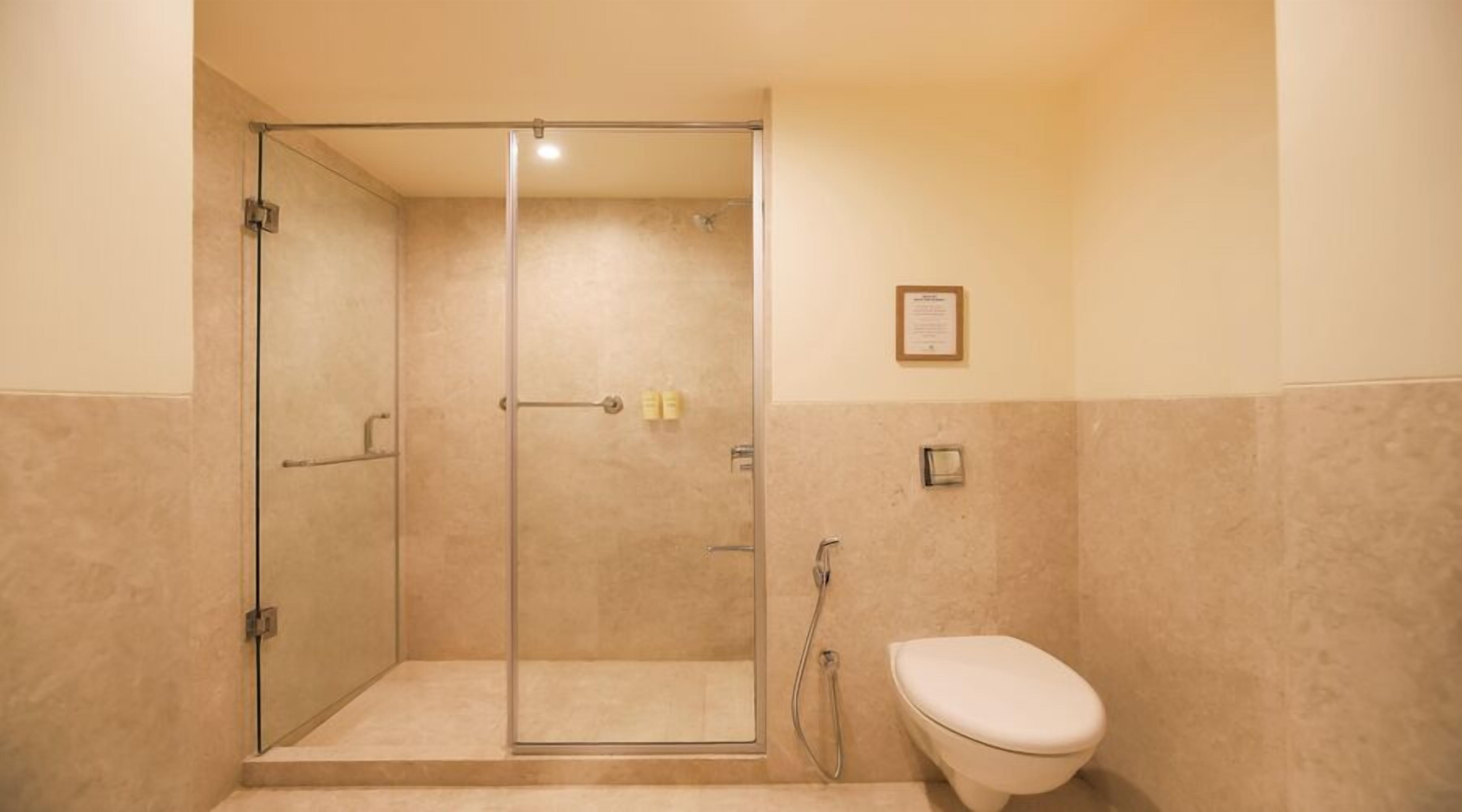 A bathroom with a glass-enclosed shower, a toilet, and a wall-mounted sink.