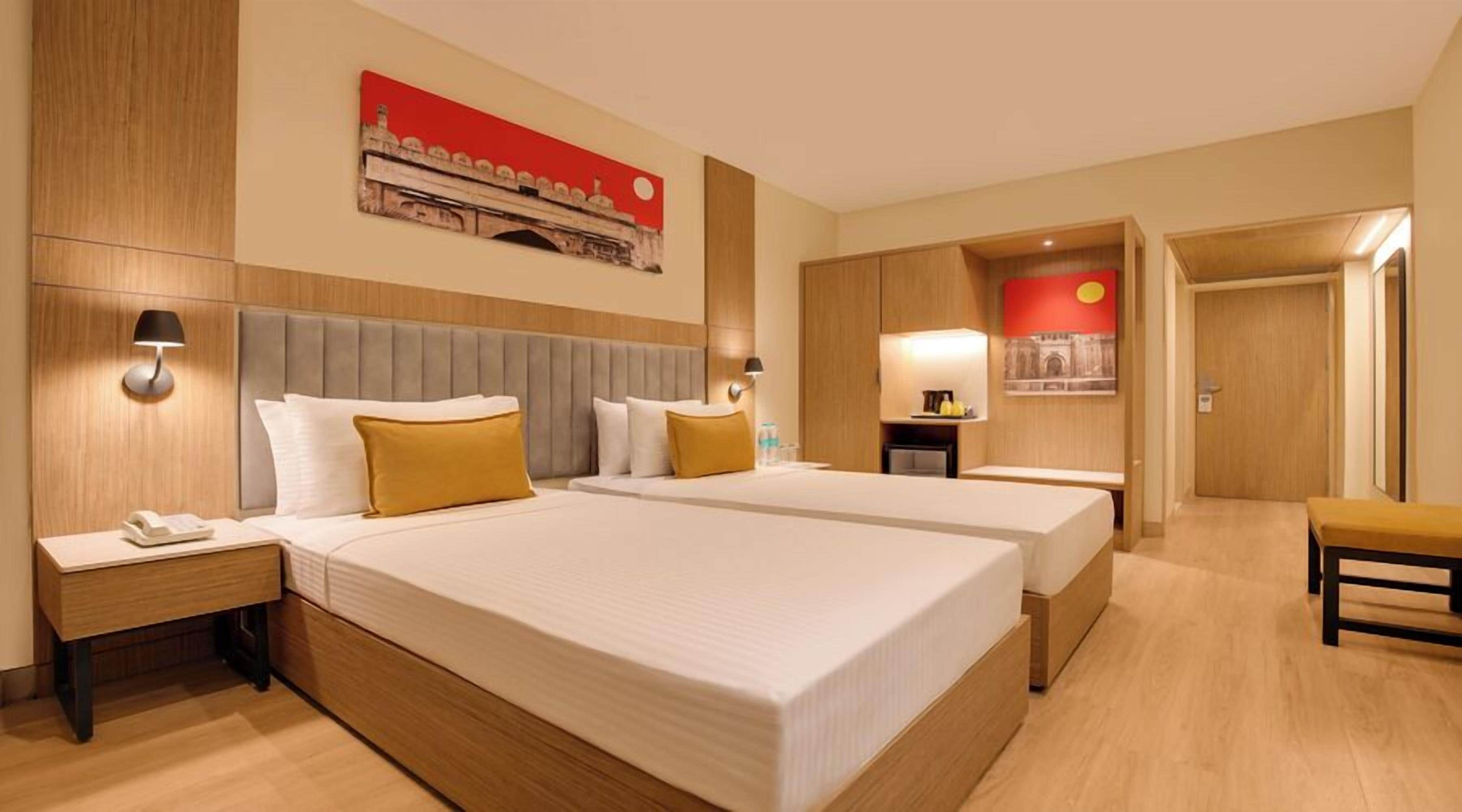 A hotel room with two beds, a desk, a chair, and a small table.