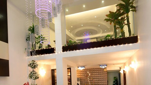 Un hôtel à plusieurs niveaux, doté d’un intérieur au design moderne, comprenant un balcon agrémenté de plantes, d’un éclairage décoratif et d’une atmosphère chaleureuse.