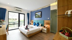 Une chambre d’hôtel avec un lit, des tables de chevet, un bureau et un balcon.