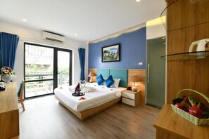 Ein Hotelzimmer mit einem Bett, Nachttischen, einem Kleiderschrank, einem Balkon und einem Fenster.