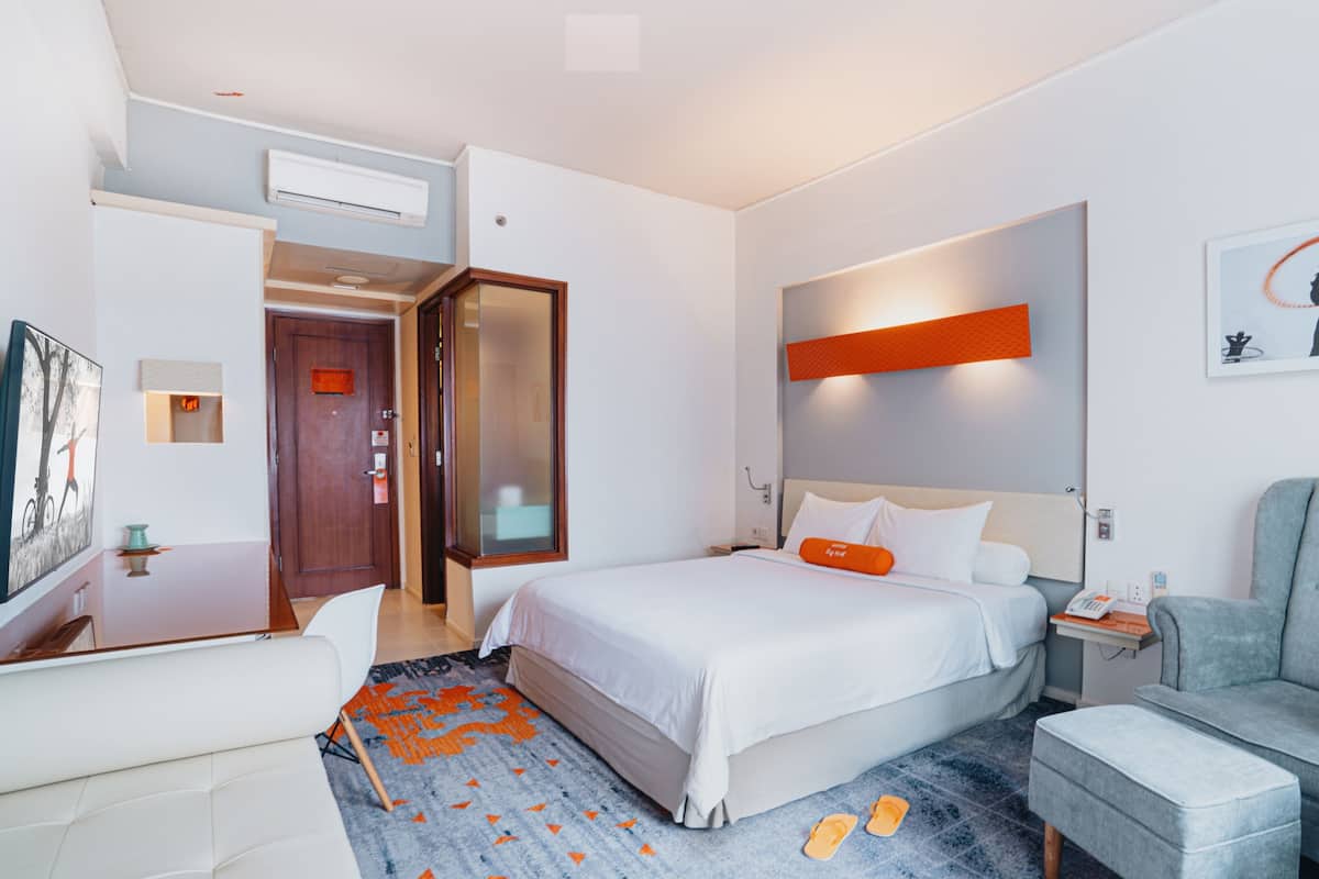 Ein Hotelzimmer mit Bett, Schreibtisch, Stuhl und einer Couch.