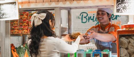 A food counter with a sign reading "The Brighter Side" and a person serving food.