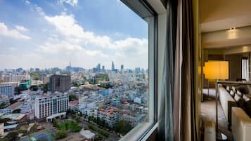 A cityscape view from a hotel room with a large window, a sofa, and a lamp.