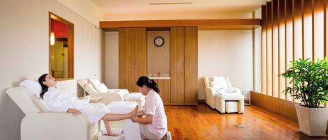 A spa room with a massage table, a massage therapist, and a foot bath.