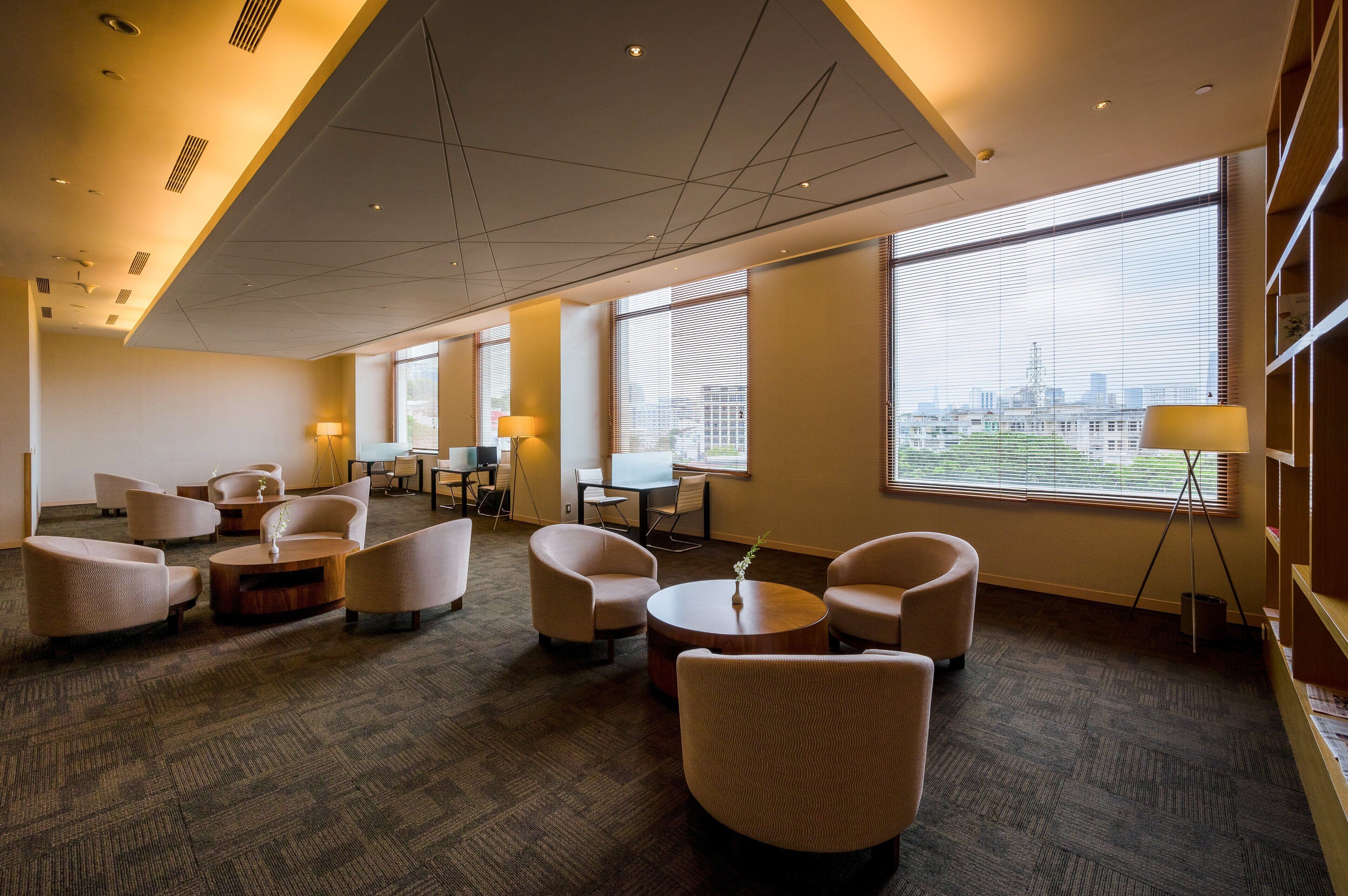 A modern hotel lobby with comfortable seating, large windows offering city views, and a clean, well-lit interior.