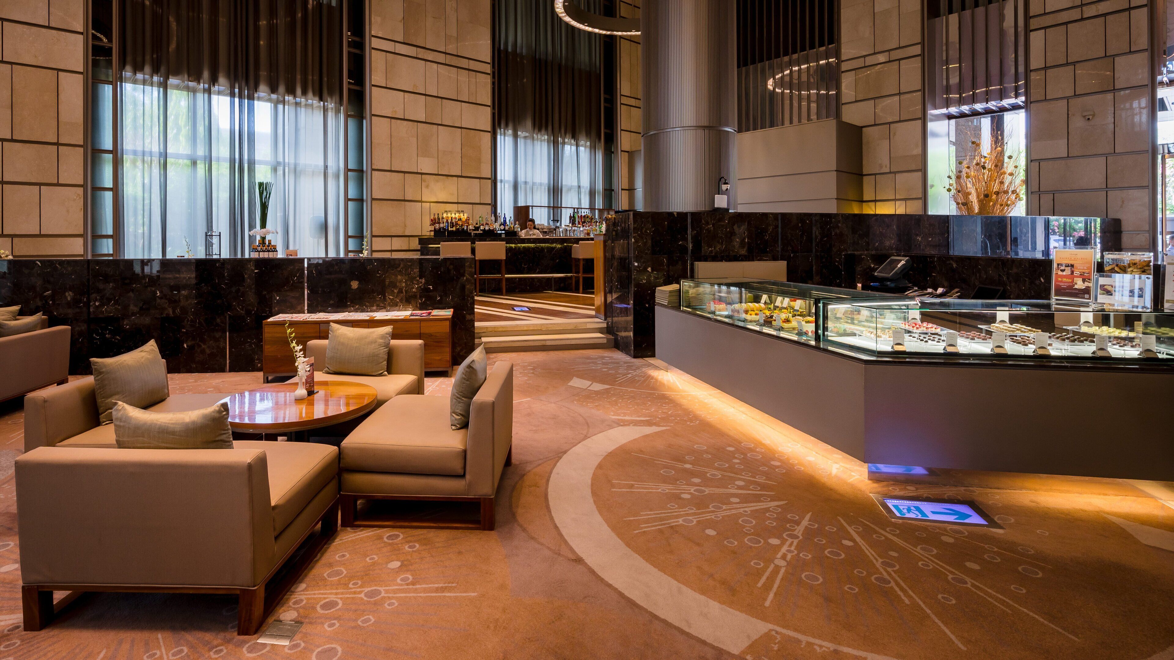 Ein moderner Lounge-Bereich mit Sofas, einem Couchtisch und einer Vitrine mit verschiedenen Gegenständen.