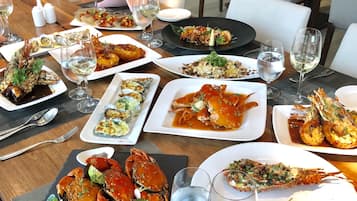 Una tavola imbandita con diversi piatti di pesce, bicchieri da vino e posate.