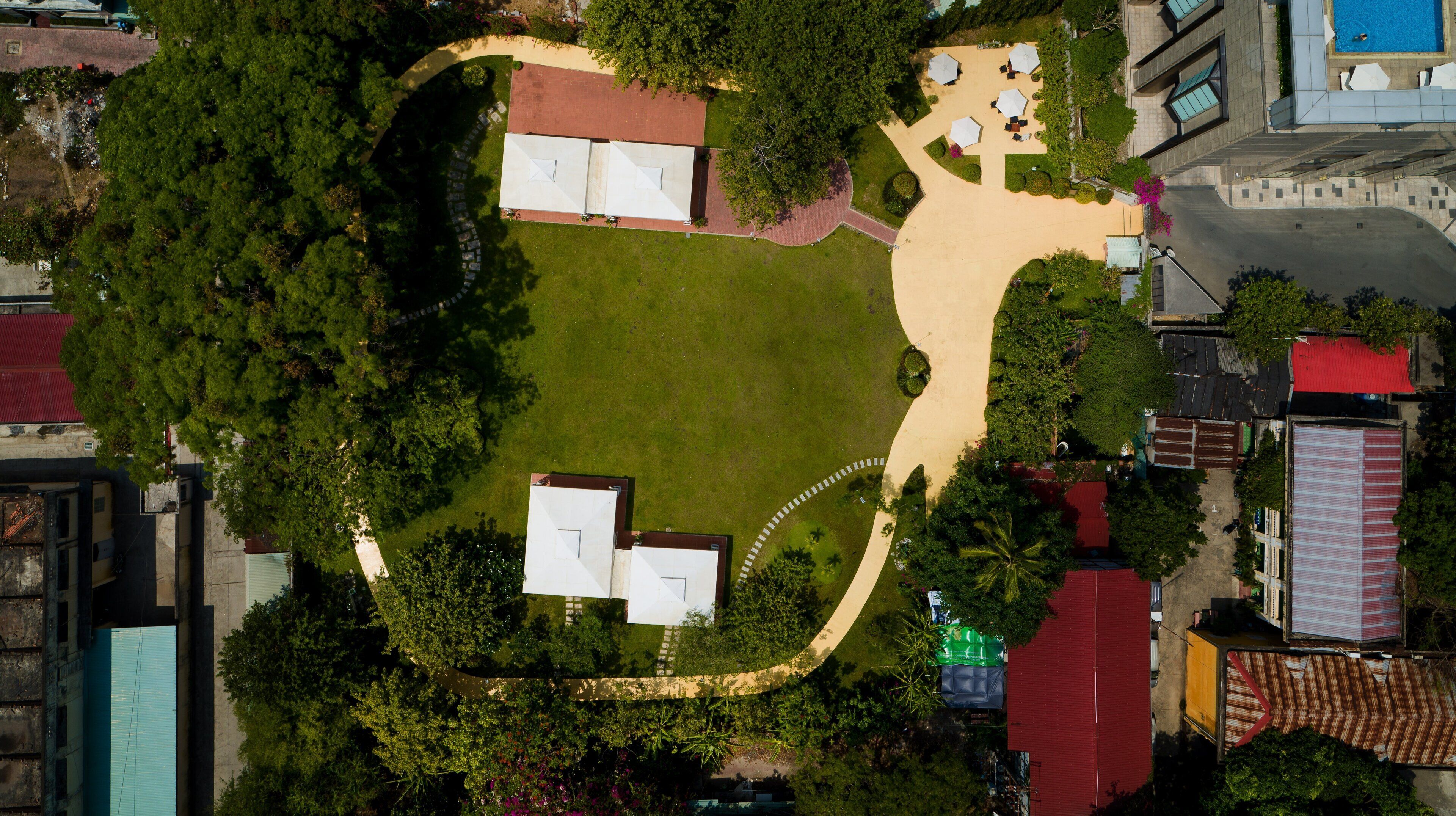 An aerial view of a property with a central lawn, surrounding buildings, and a swimming pool.