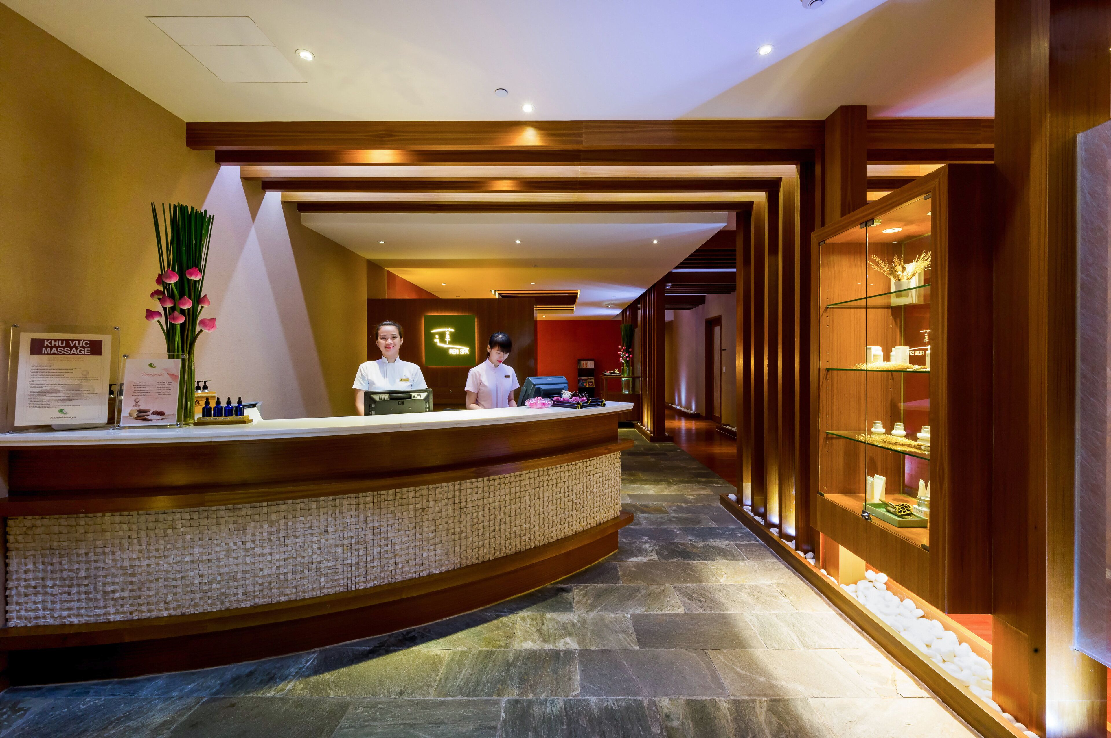 A reception area with a reception desk, a sign for a massage service, and a display of toiletries.