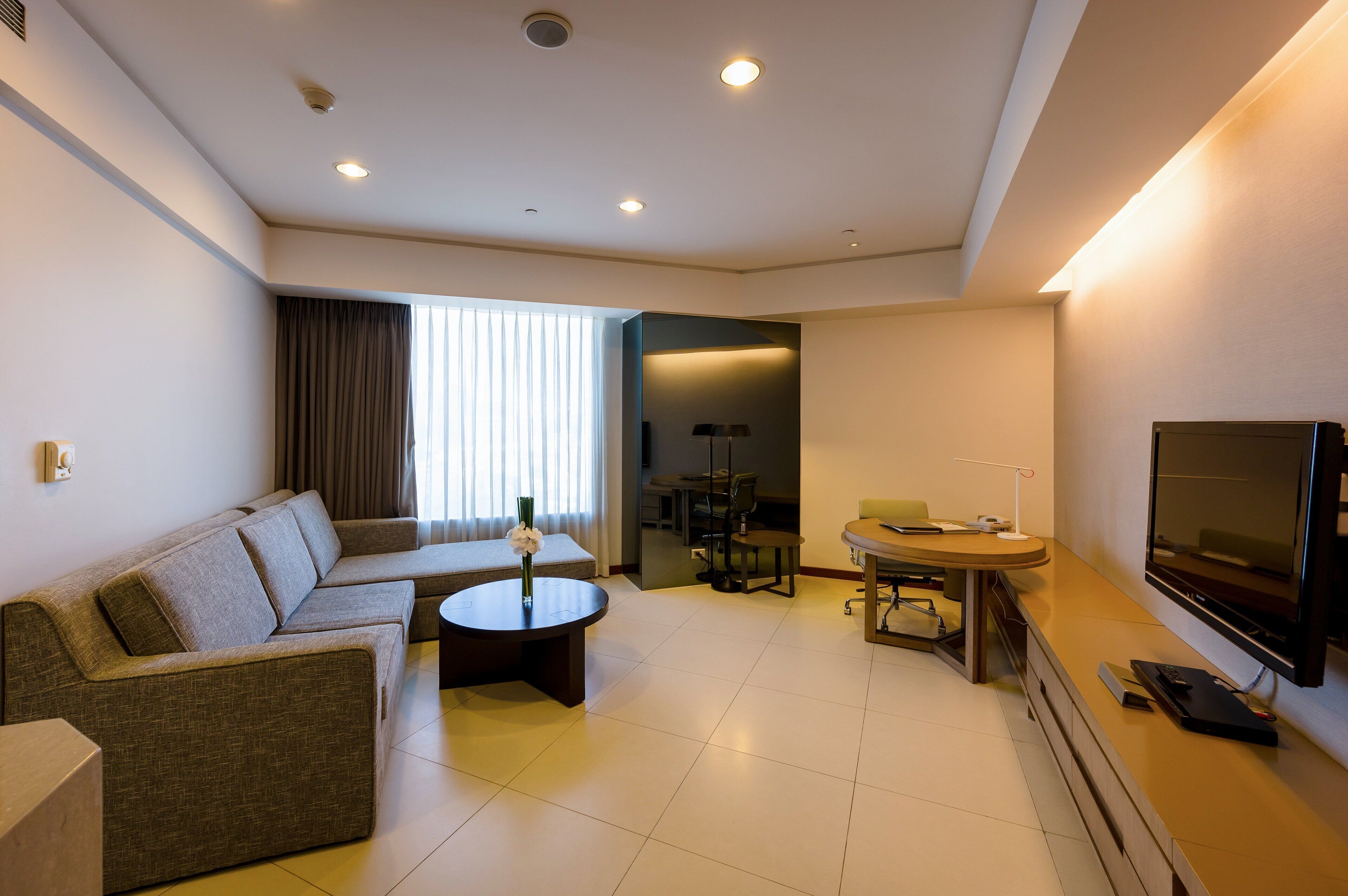 Una sala de estar moderna con sofá, mesa de centro, televisor y un comedor con mesa y sillas.