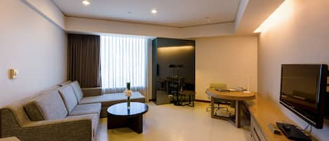 A modern living room with a sofa, coffee table, TV, and a dining area with a table and chairs.