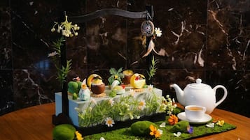 A table with a tea set, a decorative stand with a dreamcatcher, and a marble wall background.