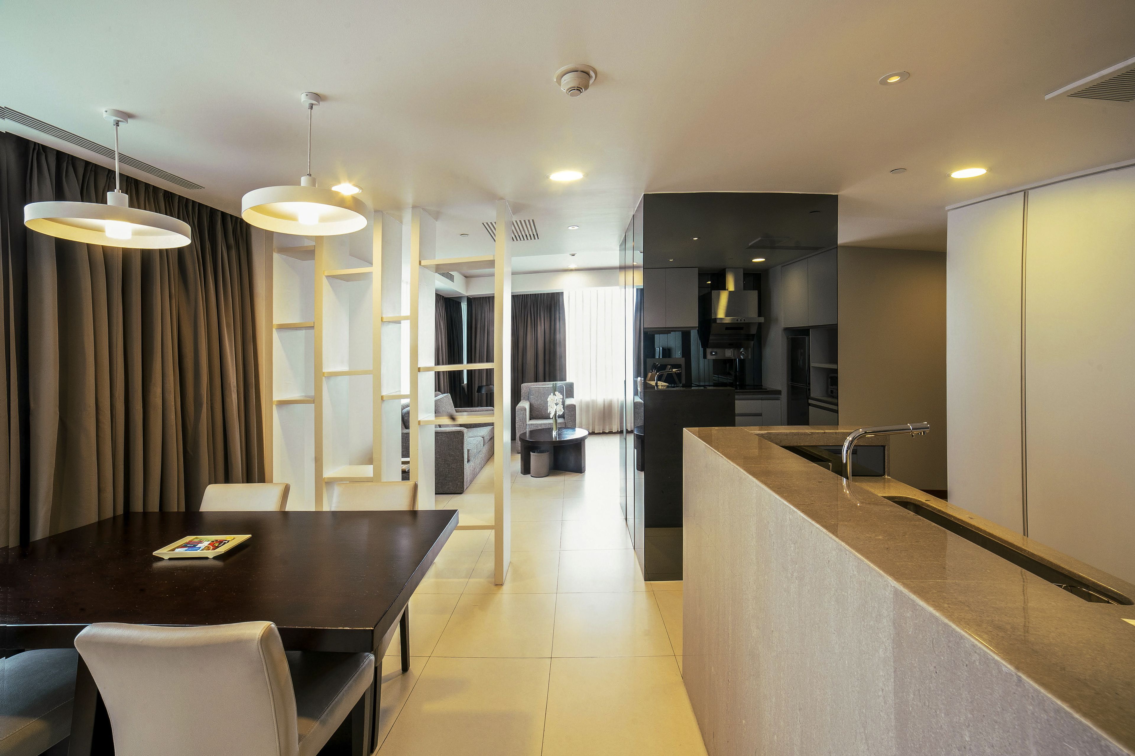 A modern hotel room with a dining area, a kitchen, and a living space.