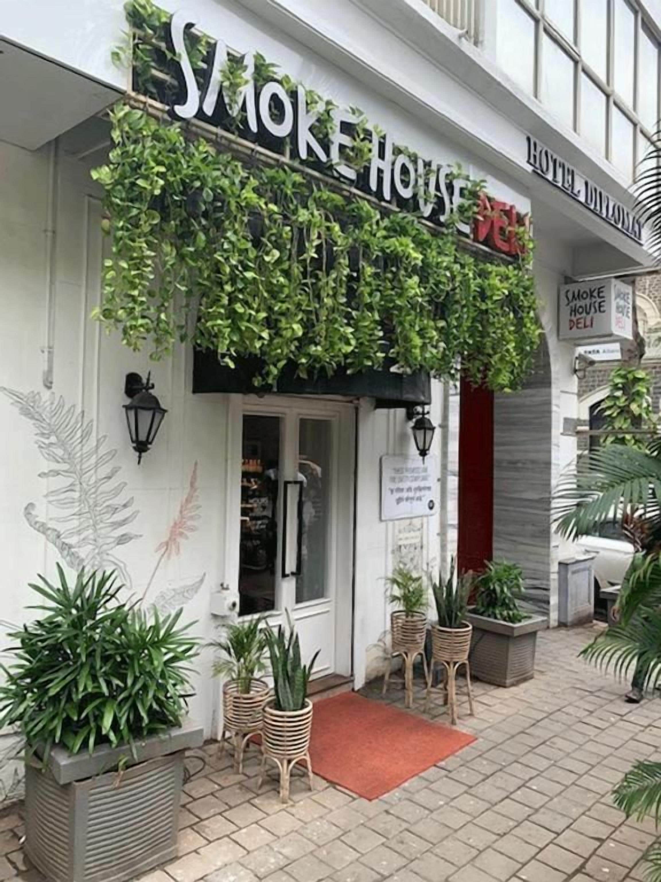 A hotel entrance with a sign reading 'SMOKE HOUSE HOTEL' and a red carpet leading to the door.