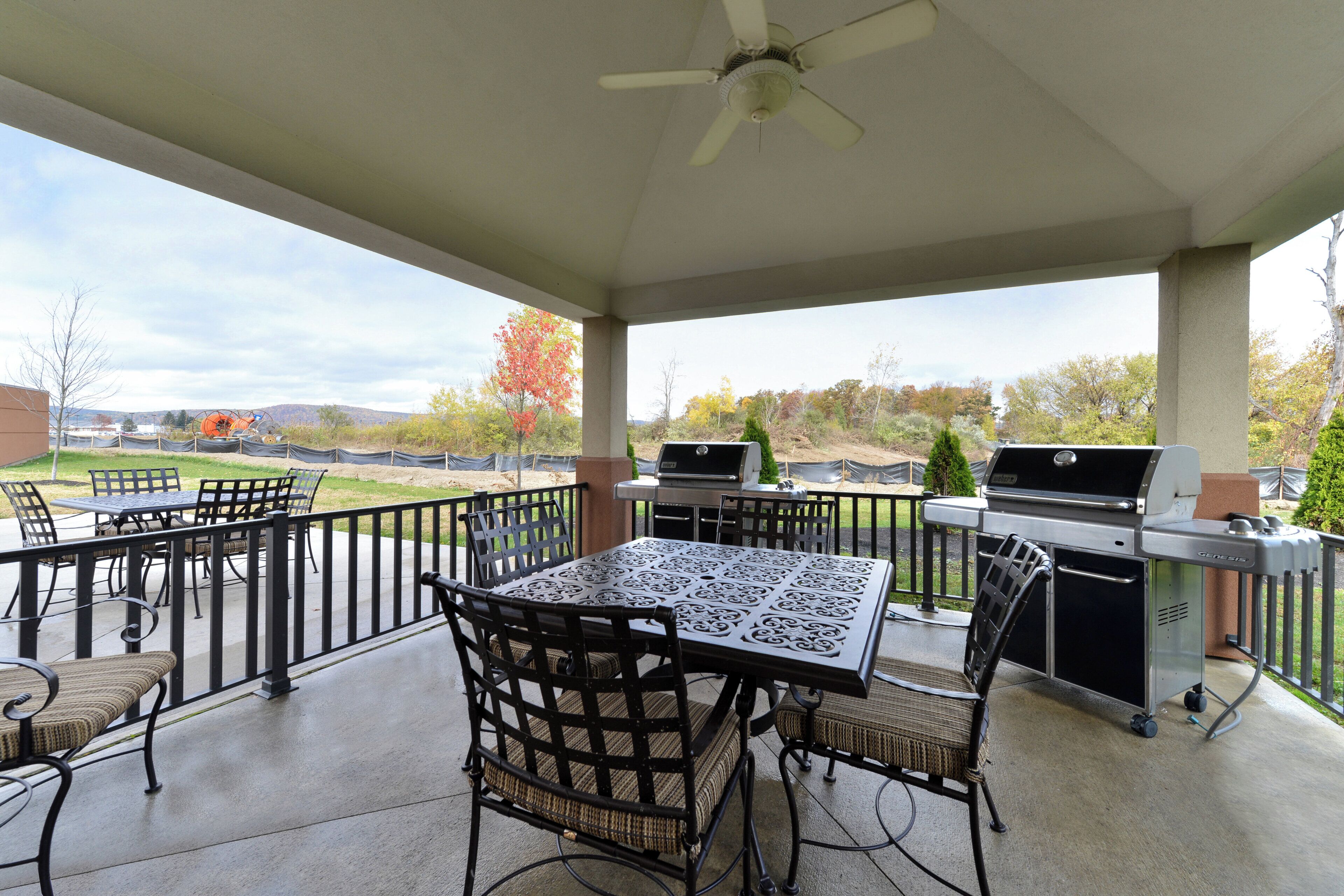A covered patio area with a table and chairs, a ceiling fan, and a grill.