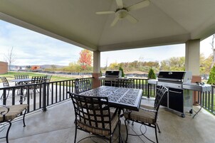 A covered patio area with a table and chairs, a ceiling fan, and a grill.