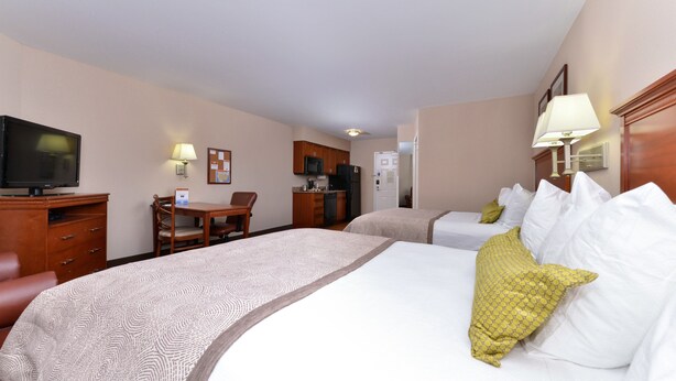 Una habitación de hotel con una cama grande, un escritorio, un televisor y un refrigerador.