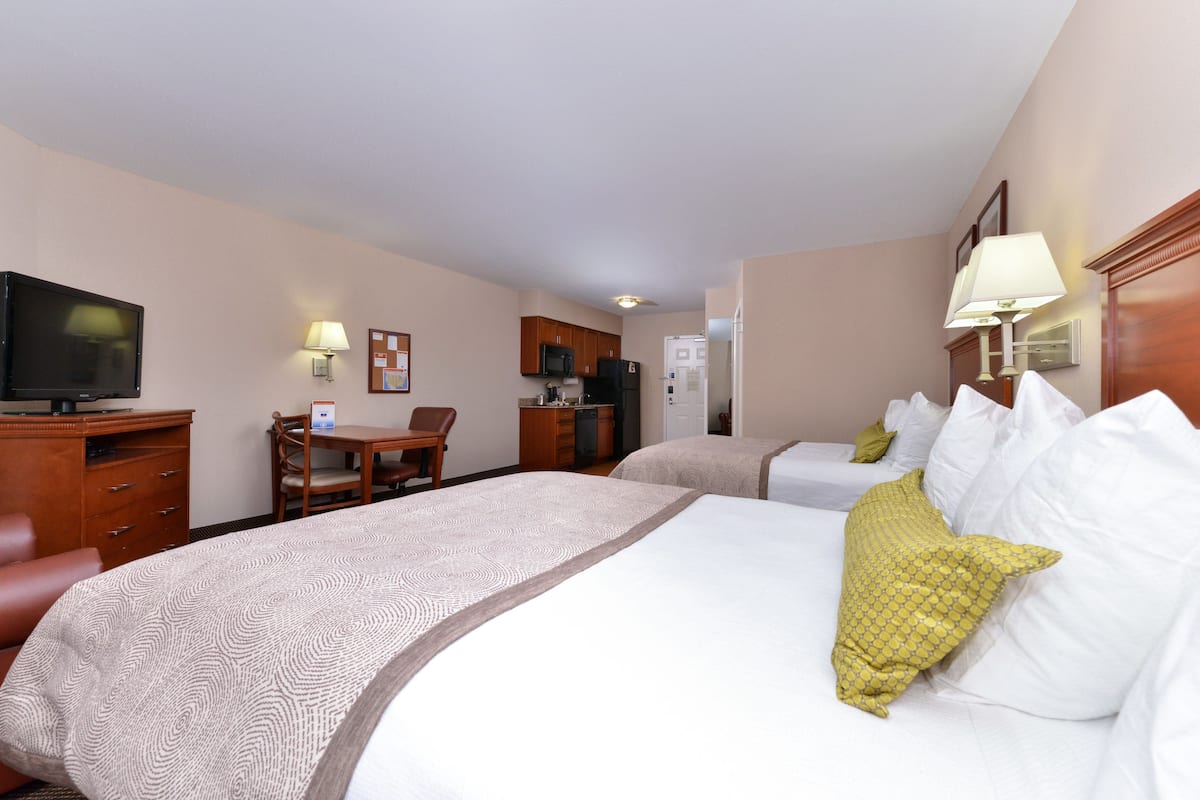 Ein Hotelzimmer mit einem großen Bett, einem Schreibtisch, einem Fernseher und einem Kühlschrank.