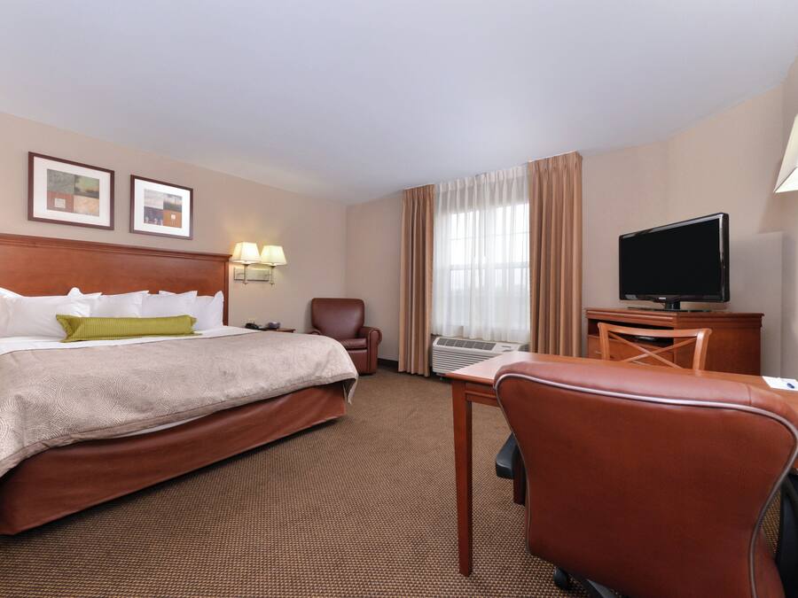 A hotel room with a bed, a desk, a chair, a television, and a window with curtains.