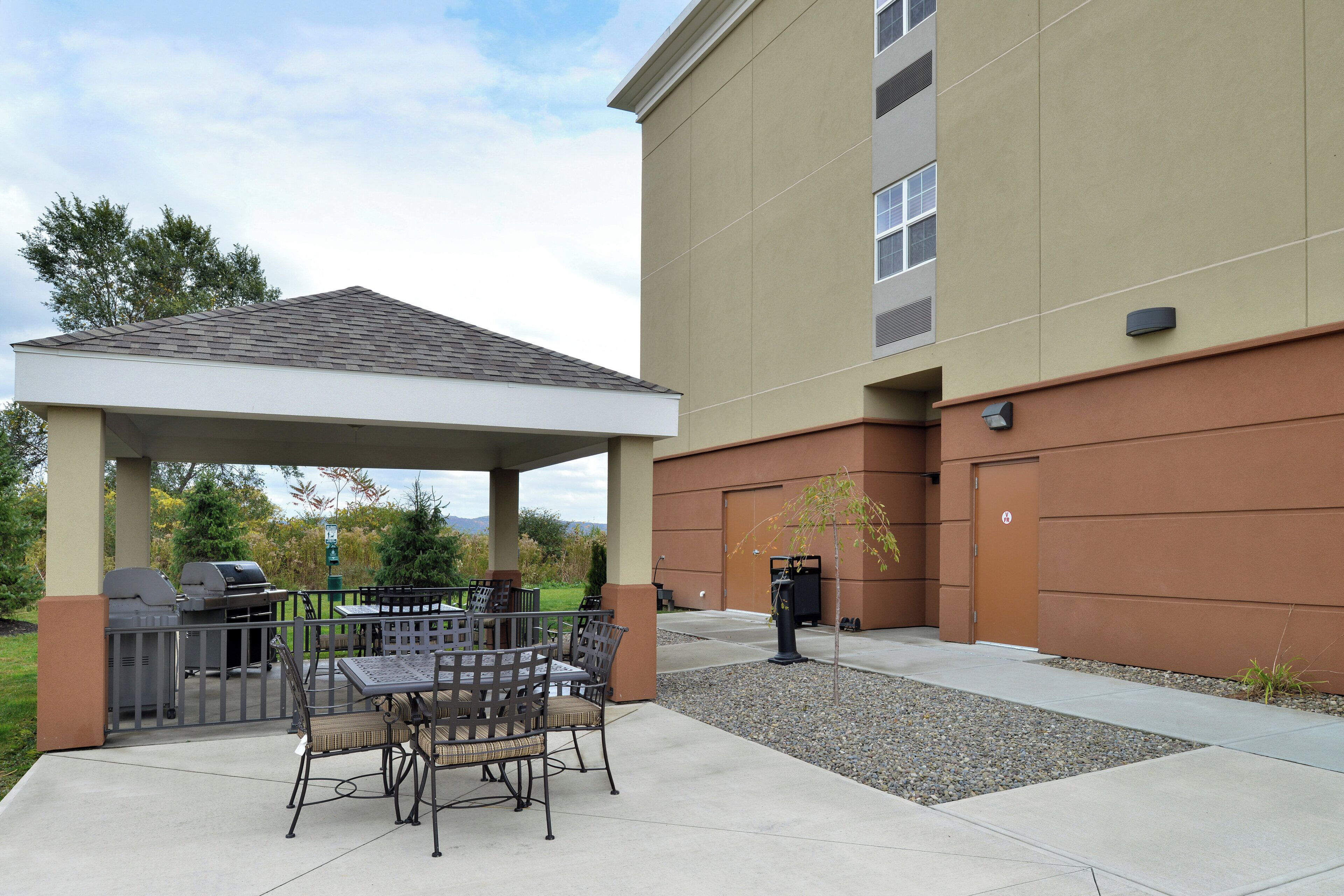 A covered patio area with outdoor seating and a barbecue grill.