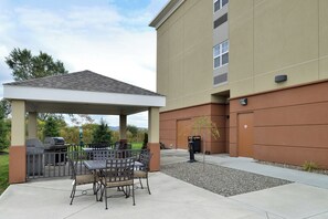 A covered patio area with outdoor seating and a barbecue grill. - Candlewood Suites Elmira Horseheads by IHG (Horseheads)