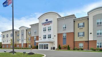 A hotel with a prominent 'Candlewood Suites' sign, multiple windows, and a landscaped entrance area.