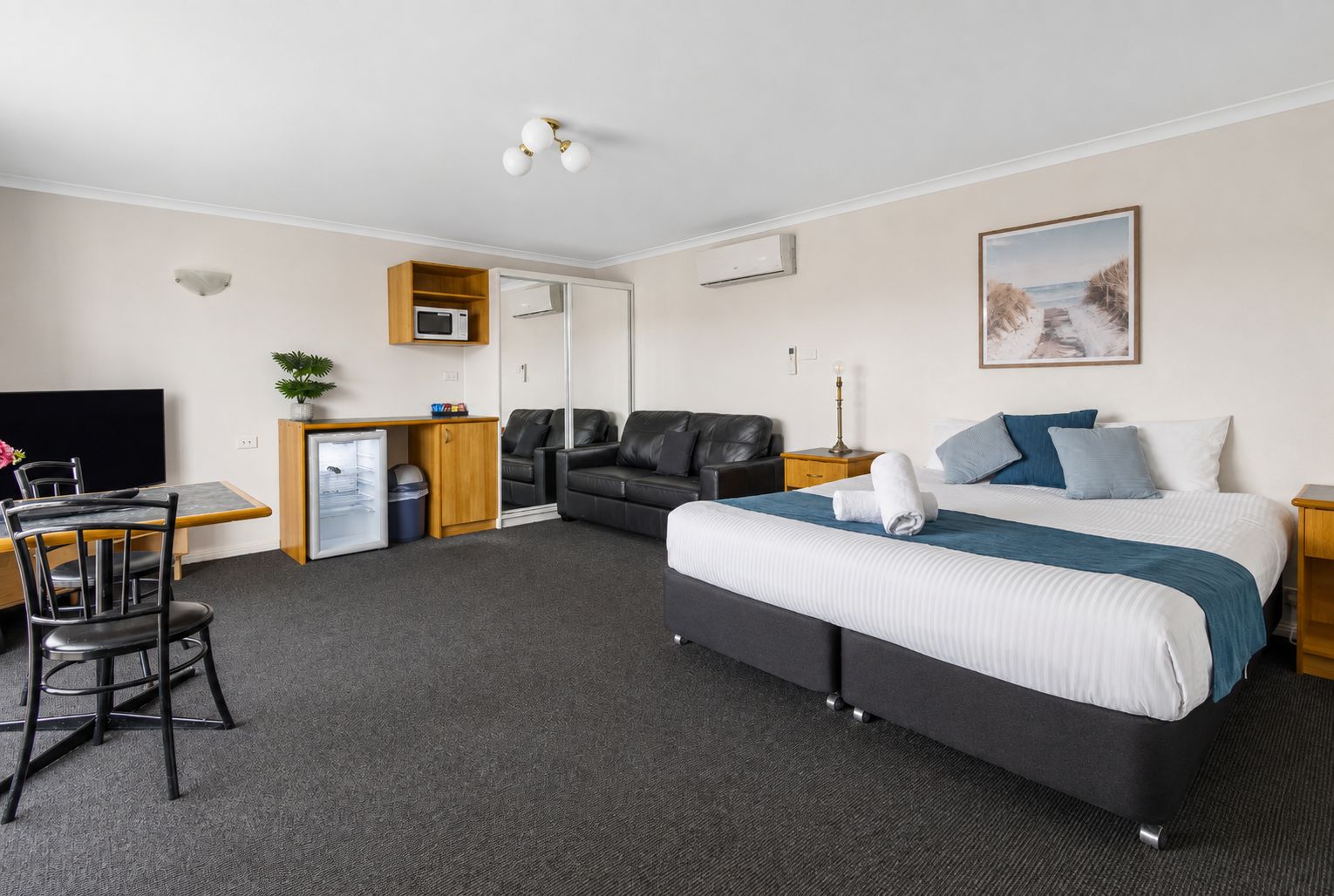 A hotel room with a bed, a desk, a chair, a television, a microwave, and a small refrigerator.